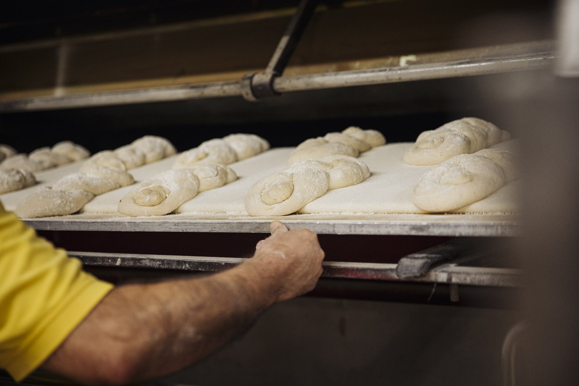 Brotteige, auf Blech, werden in Holzofen geschoben