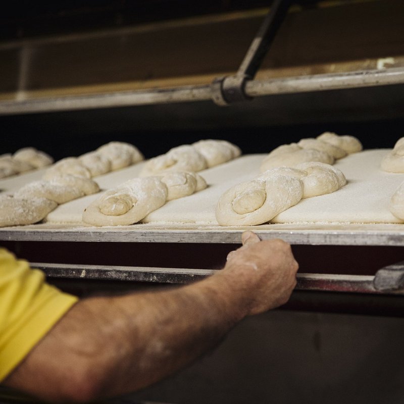 Brotteige, auf Blech, werden in Holzofen geschoben